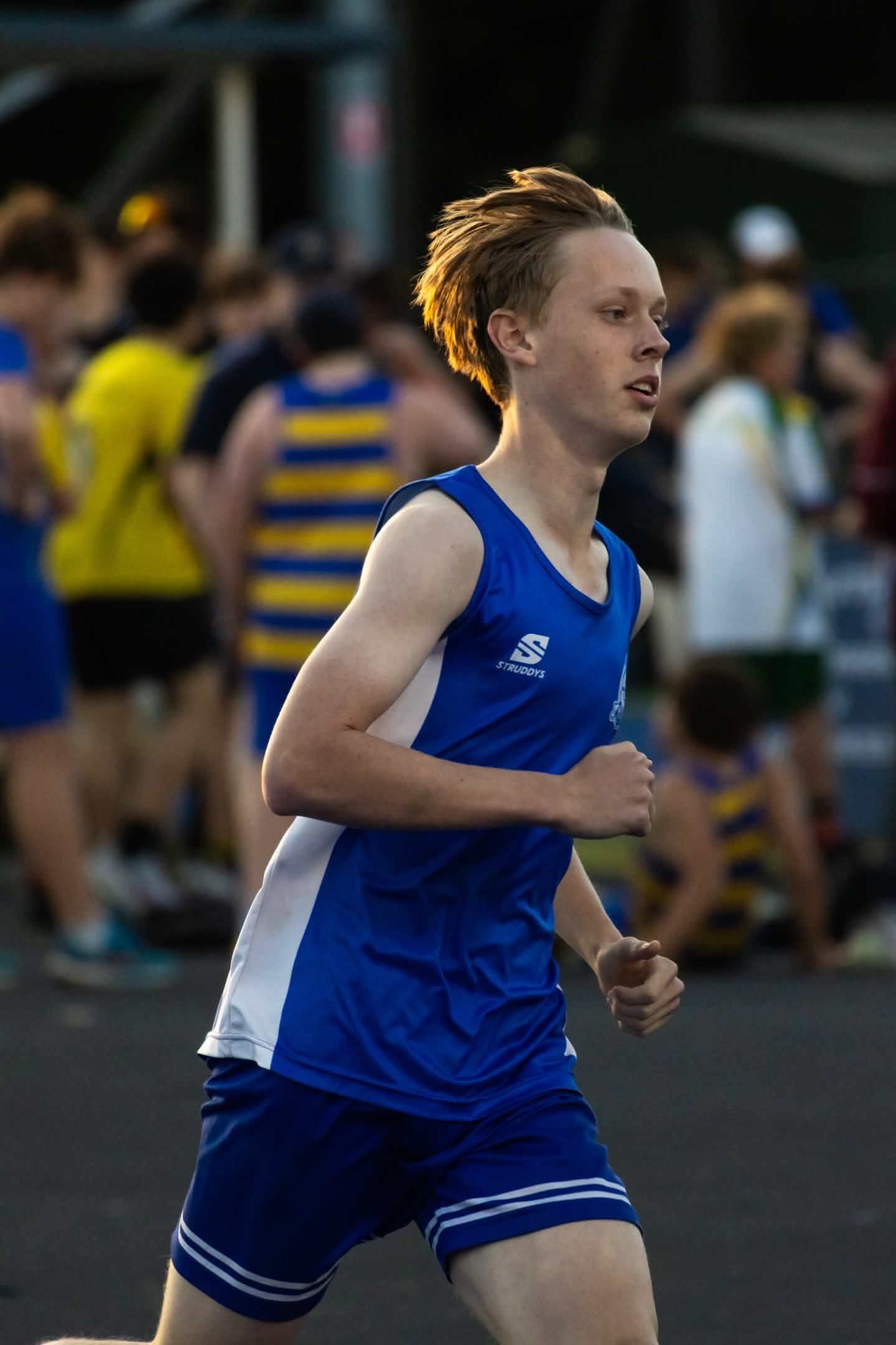 Runner in a blue uniform moving past a blurred crowd