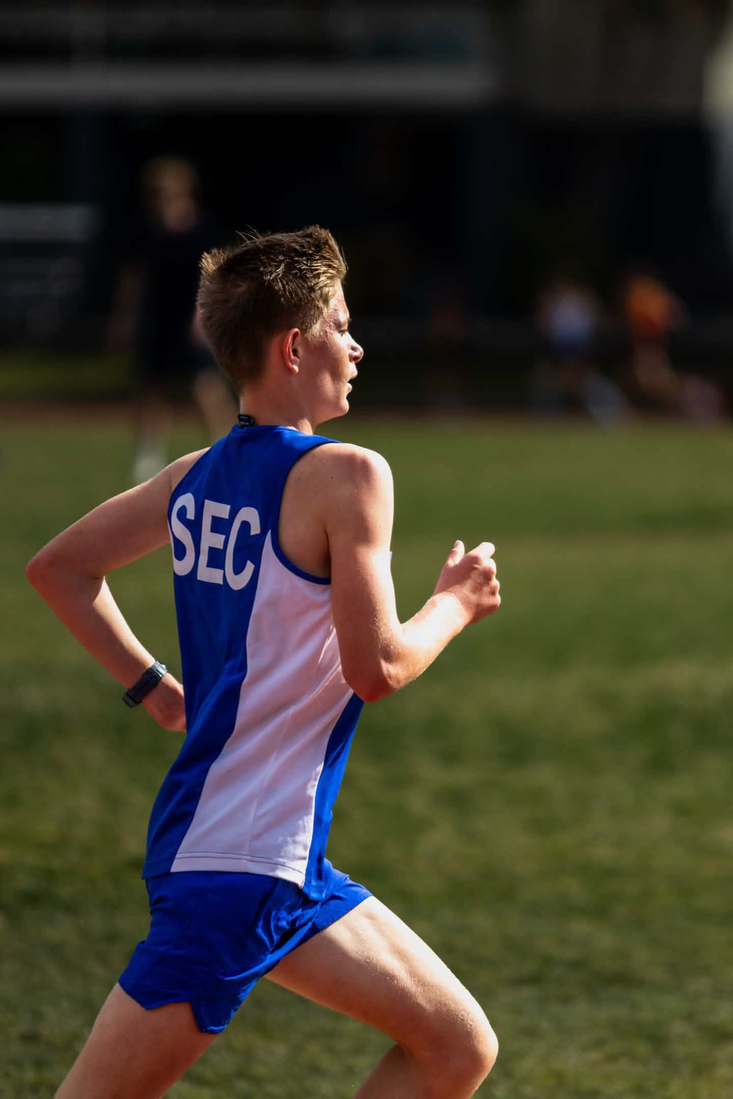 Runner in a blue uniform moving past the track during competition